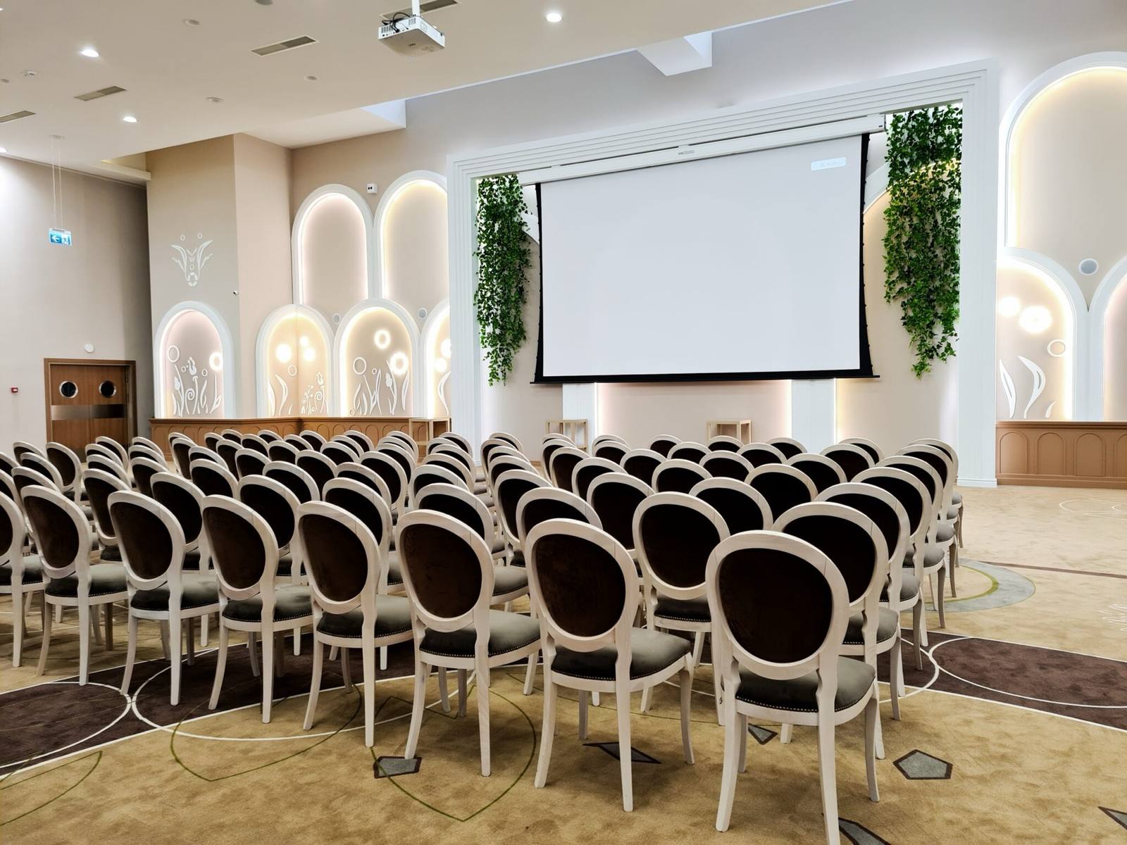 Sală aranjată pentru conferință, cu ecran de proiecție