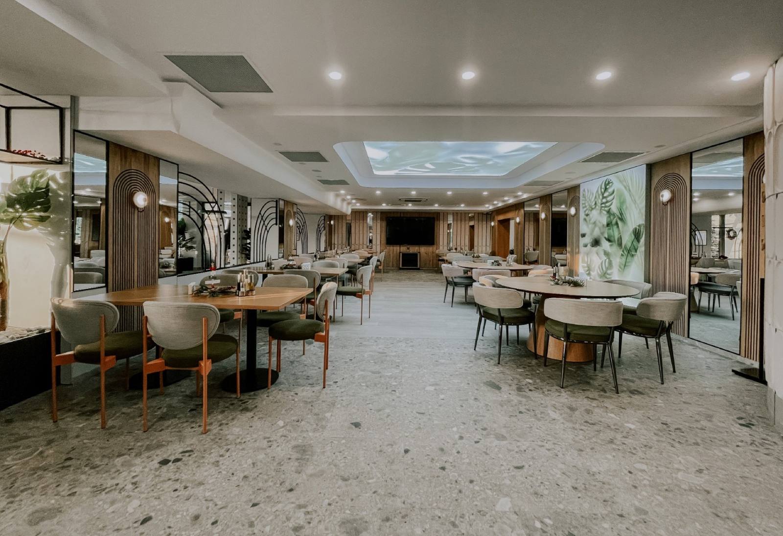 Salonul reamenajat al restaurantului — canapele verzi, arcade și lumină naturală
